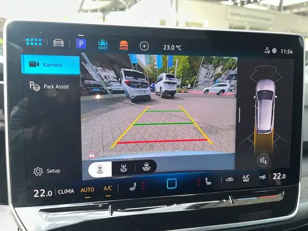 Das Bild zeigt die Innenansicht eines VW Golf Variant mit einem Bildschirm, der die Rückfahrkamera und Parkhilfefunktionen anzeigt.