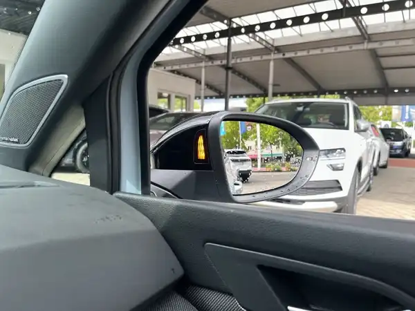 Das Bild zeigt eine Innenaufnahme des Fahrzeugs, mit einem Blick auf den Seitenspiegel und einem Blick auf andere Fahrzeuge im Hintergrund.