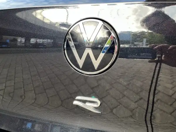 Das Bild zeigt die Rückansicht eines VW GOLF in schwarzer Farbe, mit dem VW-Logo und dem R-Symbol. Es ist eine Aufnahme von hinten, die das Logo des Fahrzeugs fokussiert.