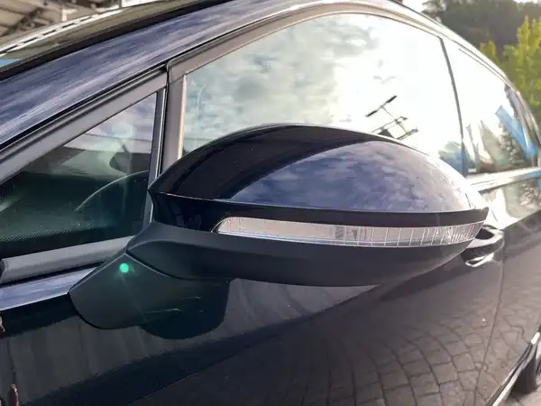 Das Bild zeigt eine seitliche Ansicht des Fahrzeugs, insbesondere den Außenspiegel. Das Fahrzeug ist schwarz.
