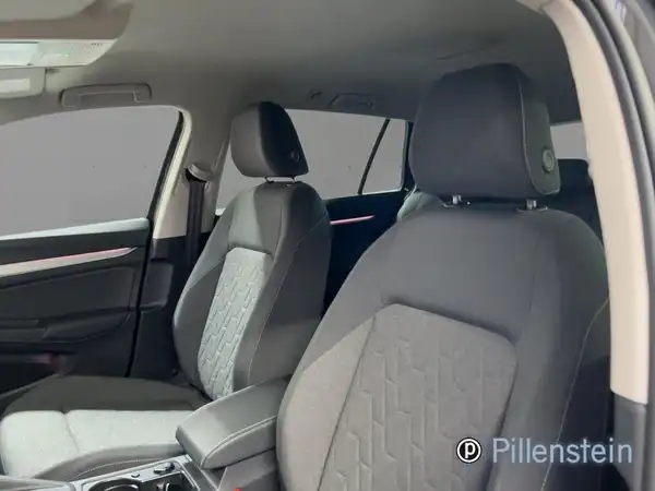 Das Bild zeigt den Innenraum eines VW Golf Variant. Es handelt sich um eine Innenaufnahme mit schwarzen Sitzen und grauen Akzenten. Ein Händlerlogo ist auf dem Bild zu sehen.