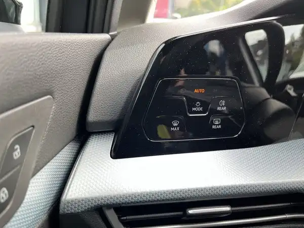 Das Bild zeigt das Innenleben eines Fahrzeugs, insbesondere ein Steuerungselement mit digitalen Anzeigen in Grau. Es enthält markante Texteinblendungen.