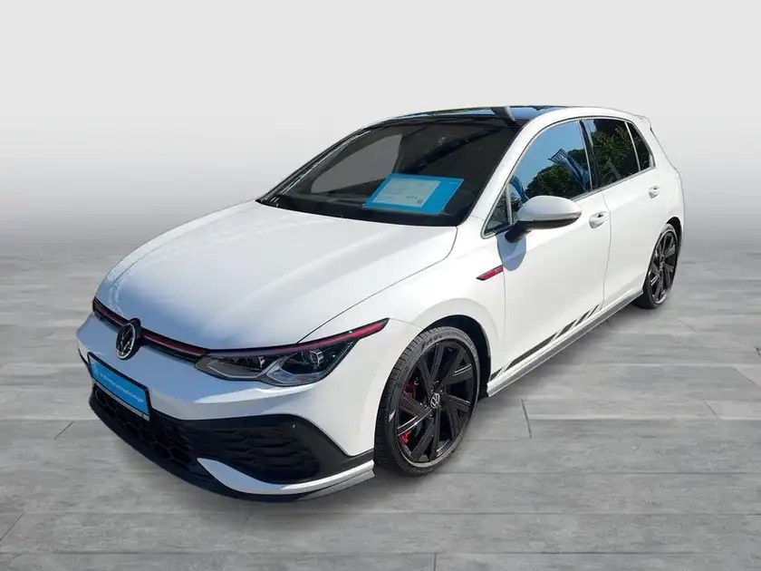 Das Bild zeigt einen weißen VW Golf GTI aus seitlicher Perspektive mit einem markanten Text auf einem Zettel auf der Frontscheibe.