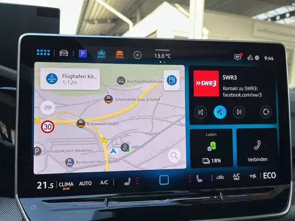 Das Bild zeigt das Innere eines Fahrzeugs mit einem Display, auf dem eine Kartenansicht und andere Funktionen angezeigt werden. Es handelt sich um einen VW Golf.