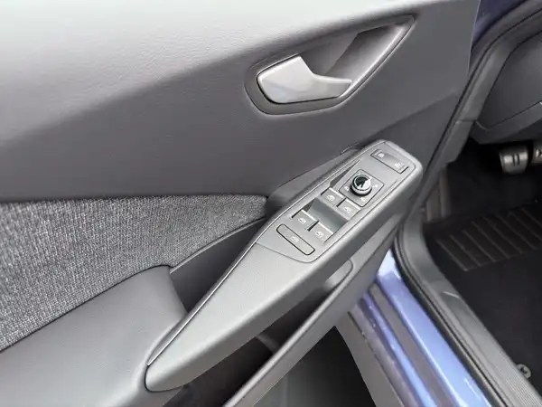 Das Bild zeigt eine Innenaufnahme der Fahrertür des VW ID.3 mit einem schwarzen Türverkleidung und den Bedienelementen.