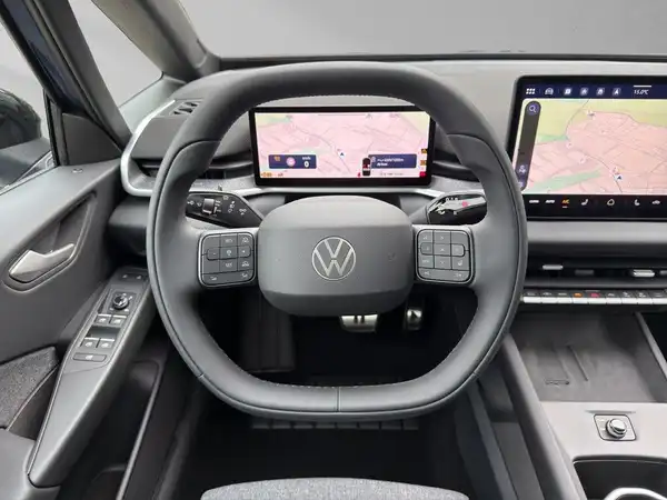 Das Bild zeigt das Innere eines VW ID.3, insbesondere das Lenkrad und das Anzeigenfeld mit Navigationsdetails. Es ist eine Innenaufnahme in schwarzer Farbgebung.
