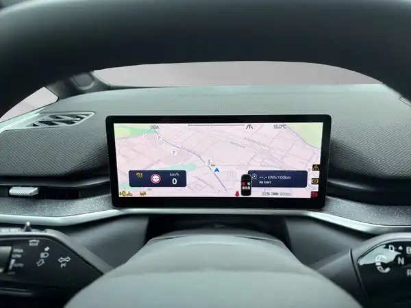 Das Bild zeigt eine Innenaufnahme des Fahrzeugs mit einem Navigationsdisplay, das eine Karte darstellt. Das Interieur ist schwarz.