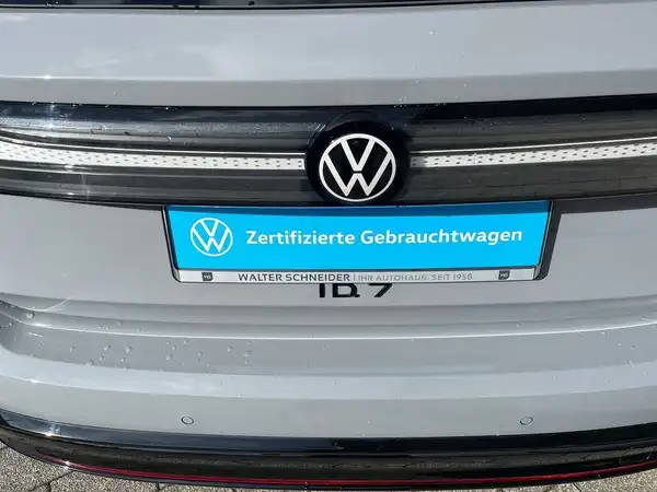 Das Bild zeigt die Rückansicht eines grauen VW ID.7 mit einem Händlerlogo und der Aufschrift "Zertifizierte Gebrauchtwagen".