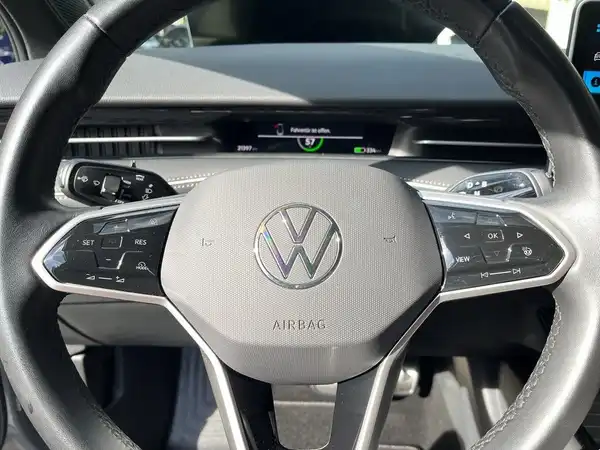 Das Bild zeigt das Innere des VW ID.7, insbesondere das Lenkrad und das Armaturenbrett. Die Interieurfarbe ist schwarz.