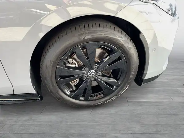 Das Bild zeigt eine Seitenansicht des Fahrzeugs, das eine silberne Farbe hat. Es ist ein Bild von dem Rad mit einem auffälligen schwarzen Felgen.