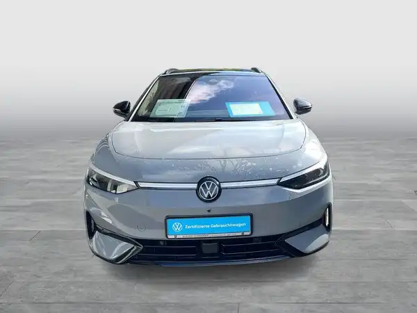 Das Bild zeigt einen grauen Volkswagen ID.7 von vorne, mit einem Händlerlogo und markanten Texteinblendungen.