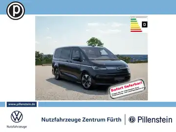 Ein seitliches Bild eines schwarzen VW Multivan, das für den Verkauf präsentiert wird. Im Hintergrund eine Landschaftsaufnahme. Das Händlerlogo ist sichtbar und enthält eine markante Texteinblendung: 'Sofort lieferbar'.