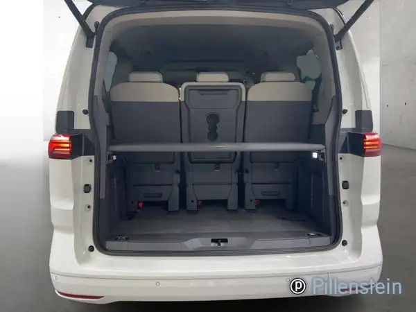 Das Bild zeigt den offenen Kofferraum eines weißen VW Multivan von hinten.