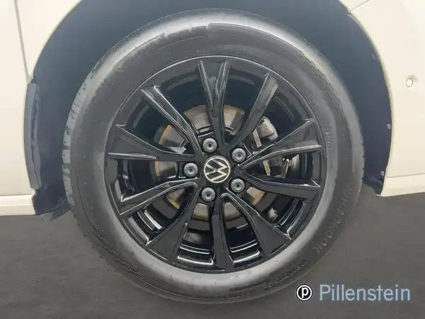 Das Bild zeigt eine Seitenansicht eines VW-Fahrzeugs, fokussiert auf das Rad mit schwarzen Felgen.