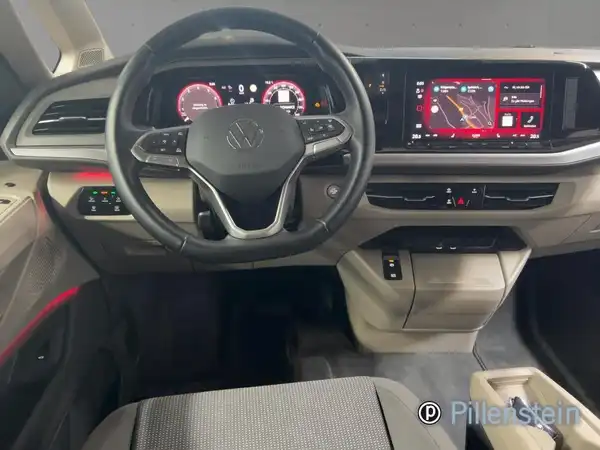 Innenansicht eines VW Multivan mit schwarzem und grauem Interieur, inklusive Lenkrad und Instrumententafel.