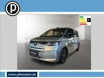 Das Bild zeigt einen VW Multivan von vorne in silberner Farbe. Es ist ein Händlerlogo vorhanden und das Bild enthält markante Texteinblendungen.