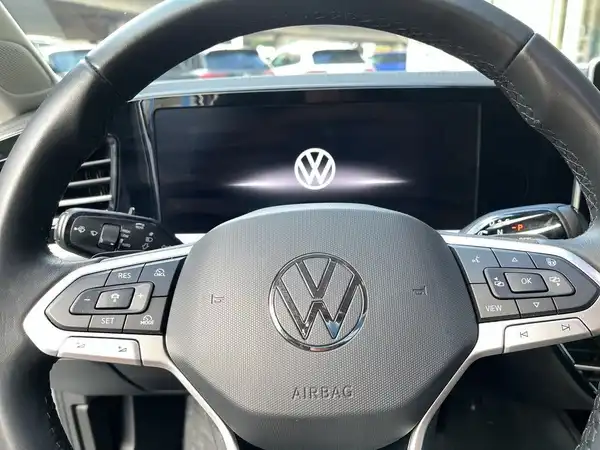 Das Bild zeigt das Innere eines VW Passat Variant, mit Fokus auf das Lenkrad und das zentrale Display. Die Interieurfarbe ist schwarz.