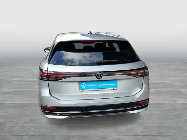 Das Bild zeigt einen silberfarbenen VW Passat Variant von hinten. Es enthält ein Händlerlogo und eine markante Texteinblendung.