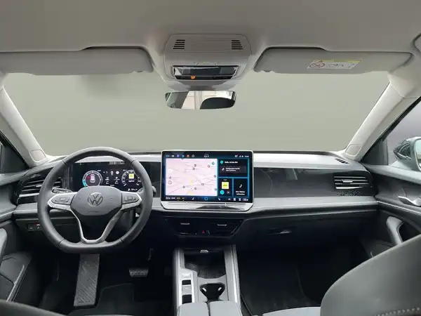 Das Bild zeigt das Innenraum eines VW Passat Variant, mit einem modernen digitalen Armaturenbrett und Navigationsbildschirm.