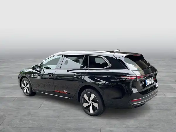 Das Bild zeigt einen schwarzen VW Passat Variant von der Seite. Auf dem Fahrzeug ist ein Händlerlogo sichtbar, sowie markante Texteinblendungen.