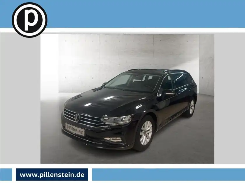 Das Bild zeigt einen schwarzen Volkswagen Passat Variant, aufgenommen von vorne. Im Hintergrund ist eine neutrale Kulisse zu sehen. Das Händlersymbol ist im oberen linken Bereich sichtbar.