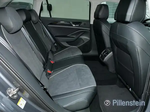 Foto zeigt die Rücksitzbank eines VW Passat Variant in schwarzem Interieur. Händlerlogo ist sichtbar.
