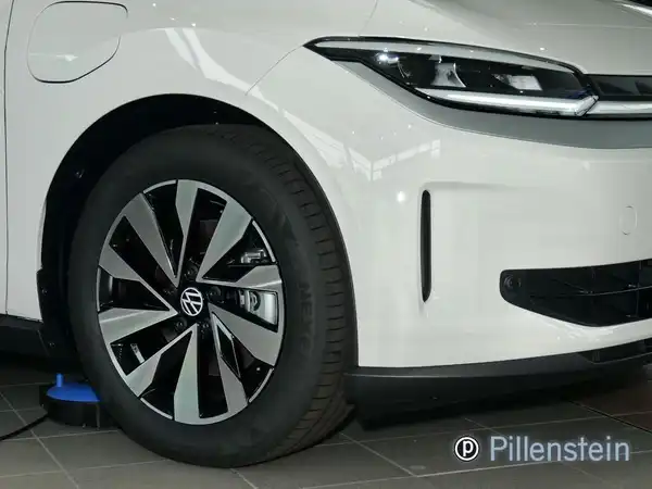 Das Bild zeigt die Vorderseite eines weißen VW Polo, aufgenommen aus einem Vorderansicht-Blickwinkel in einem Ausstellungsraum. Das Händlerlogo "Pillenstein" ist sichtbar.