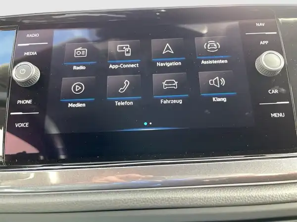 Innenaufnahme des Fahrzeugs VW Polo mit dem Infotainmentsystem und verschiedenen Bedienelementen auf dem Bildschirm. Das Interieur ist schwarz.
