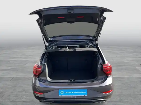 Das Bild zeigt den offenen Kofferraum eines grauen VW Polo, aufgenommen von hinten.