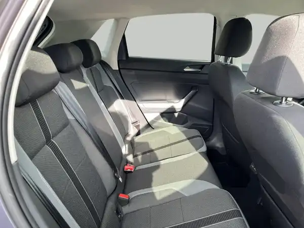 Das Bild zeigt den Innenraum des Fahrzeugs, insbesondere die Rücksitze in Schwarz mit gestreiften Sitzbezügen.