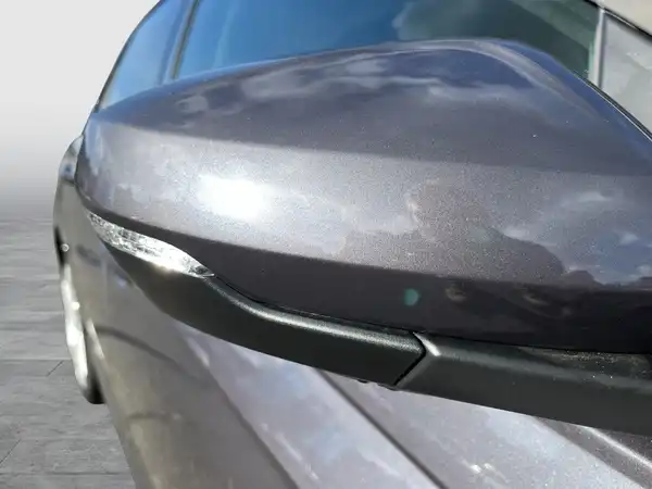 Das Bild zeigt den seitlichen Spiegel eines grauen VW Polo von der Seite aufgenommen.
