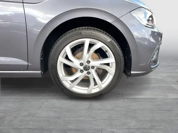 Das Bild zeigt die Seite eines grauen VW Polo mit einem Fokus auf den Reifen und der Felge.