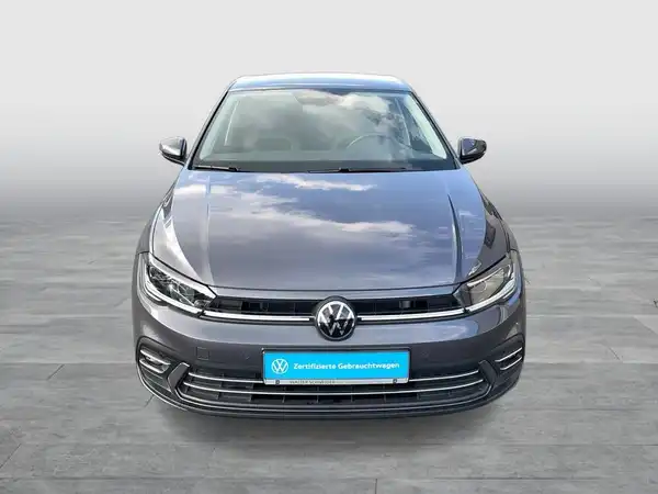 Ein Bild eines grauen VW Polo, aufgenommen von vorne, mit einem Händlerschild im Bild.