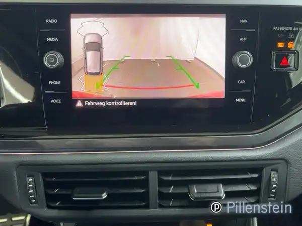 Eine Innenaufnahme des VW Polo GTI, die das Navigations- und Rückfahrkameradisplay zeigt. Das Interieur ist schwarz. Es gibt ein Händlerlogo und markante Texteinblendungen.