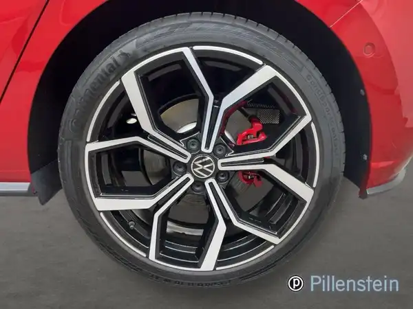 Das Bild zeigt das Rad eines roten VW Polo GTI aus seitlicher Perspektive. Das Fahrzeug hat sportliche Felgen, und das Händlersymbol ist sichtbar.