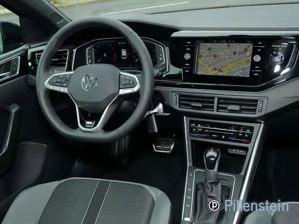 Bild eines VW Polo Innenraums, mit schwarzem Interieur und grauen Akzenten. Händlerinformationen sind im Bild enthalten.