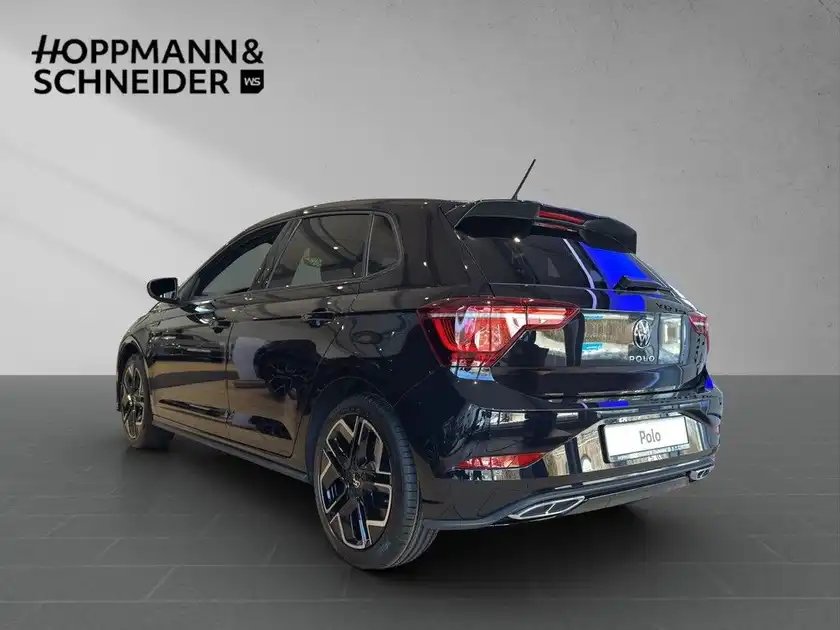 Das Bild zeigt einen schwarzen VW Polo von der Seite, aufgenommen in einer modernen Präsentation, mit dem Händlerlogo im oberen Bereich.