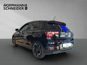 Das Bild zeigt einen schwarzen VW Polo von der Seite, aufgenommen in einer modernen Präsentation, mit dem Händlerlogo im oberen Bereich.