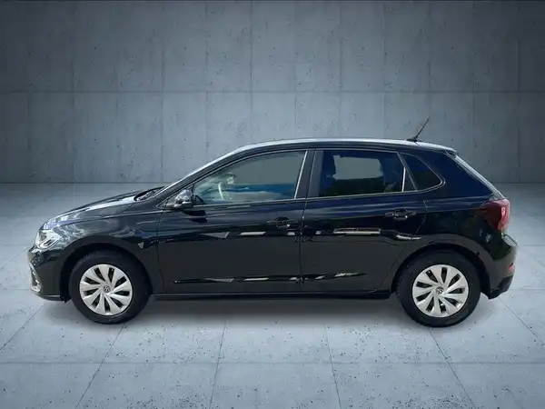 Das Bild zeigt einen VW Polo von der Seite in schwarzer Farbe, aufgenommen in einem neutralen, grauen Umfeld.
