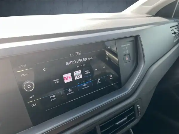 Das Bild zeigt das Innere eines Fahrzeugs, mit einem schwarzen Armaturenbrett und einem Infotainment-Display, das Informationen anzeigt.