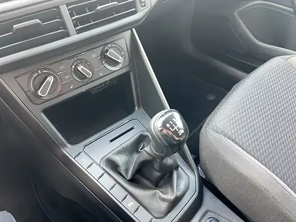 Das Bild zeigt den Innenraum eines VW Polo mit einem schwarzen Stoffbezug. Die Aufnahme zeigt den Schalthebel und die Bedienelemente.