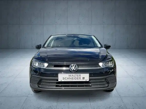 Das Bild zeigt einen schwarzen Volkswagen Polo aus der Frontalansicht, mit einem Händlerlogo und auffälligen Texteinblendungen.