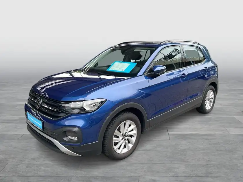 Das Bild zeigt einen blauen VW T-Cross, aufgenommen von der Seite. Auf dem Fahrzeug ist ein Blatt mit markanten Texteinblendungen zu sehen.