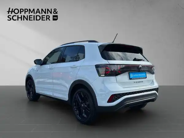 Das Bild zeigt ein weißes Fahrzeug (VW T-CROSS) aus der seitlichen Ansicht. Das Händlerlogo "HOPPMANN & SCHNEIDER" ist eingeblendet.