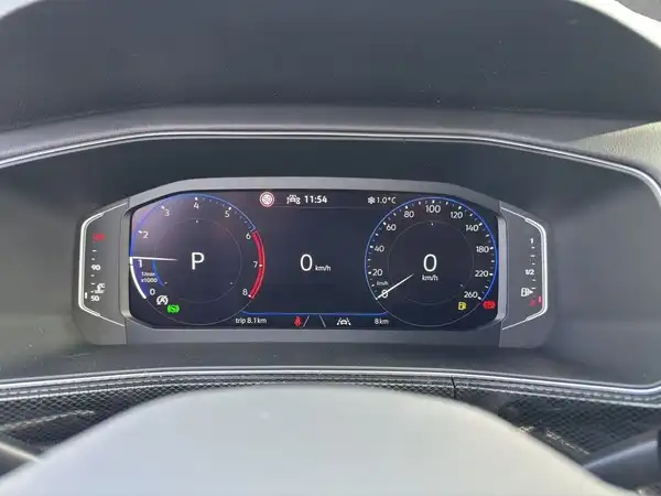Das Bild zeigt das Armaturenbrett eines VW T-CROSS mit einem digitalen Tacho und Geschwindigkeitsmesser. Der Innenraum ist schwarz.