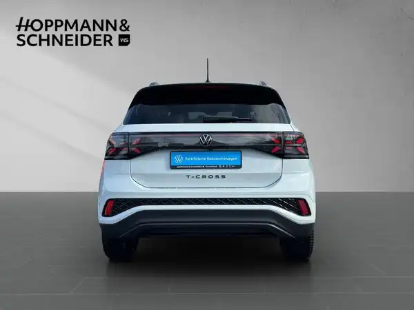 Das Bild zeigt einen weißen VW T-CROSS von hinten. Im oberen Bereich ist das Händlerlogo von HOPPMANN & SCHNEIDER eingeblendet.