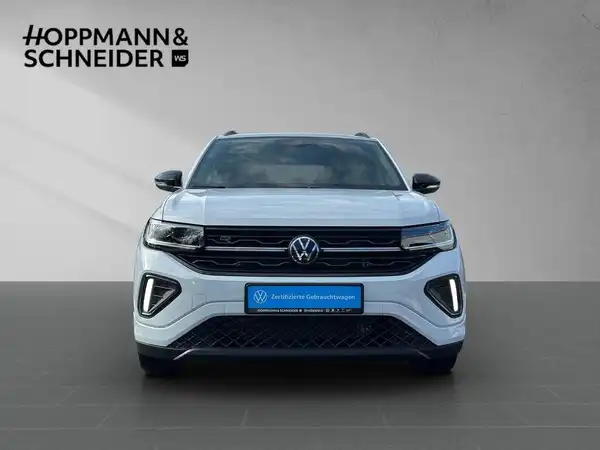Das Bild zeigt einen weißen VW T-CROSS von vorne. Es enthält das Händlerlogo "HOPPMANN & SCHNEIDER" sowie einen markanten Texteinblendung.