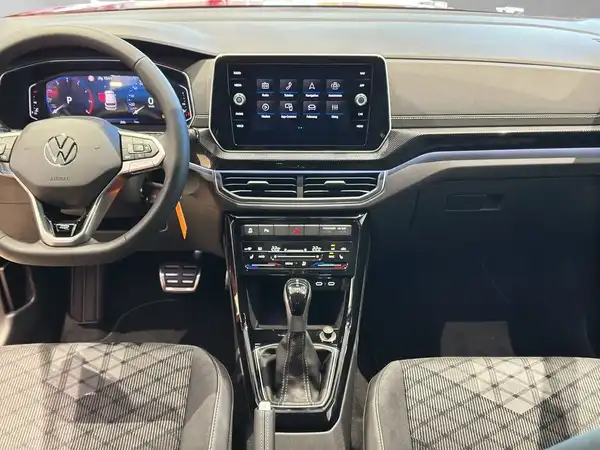 Das Bild zeigt das Innenraum eines VW T-Cross, mit einem schwarzen Interieur und grauen, karierten Sitzen.