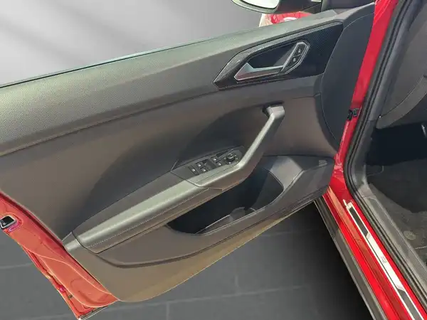 Das Bild zeigt die Türinnenseite eines VW T-Cross in Rot mit einem schwarzen Innenraum. Es handelt sich um eine Innenaufnahme.