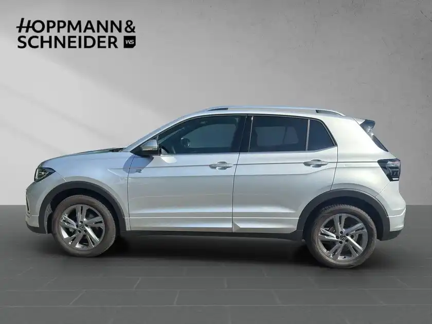 Das Bild zeigt einen VW T-Cross von der Seite in silberner Farbe. Im Hintergrund ist das Händlerlogo 'HOPPMANN & SCHNEIDER' sichtbar.